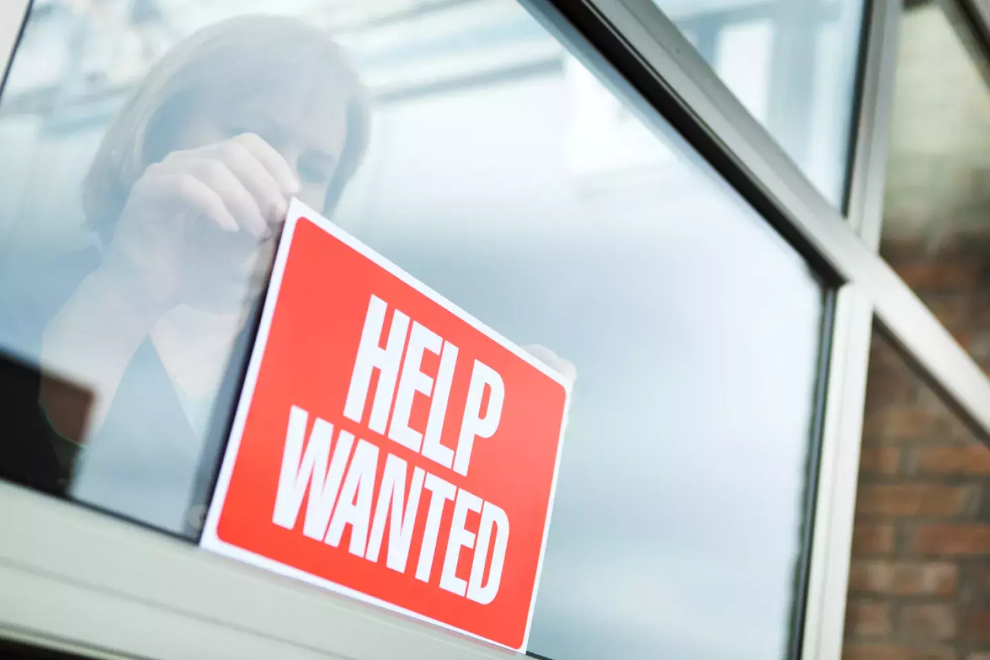 Woman in store putting out help wanted sign