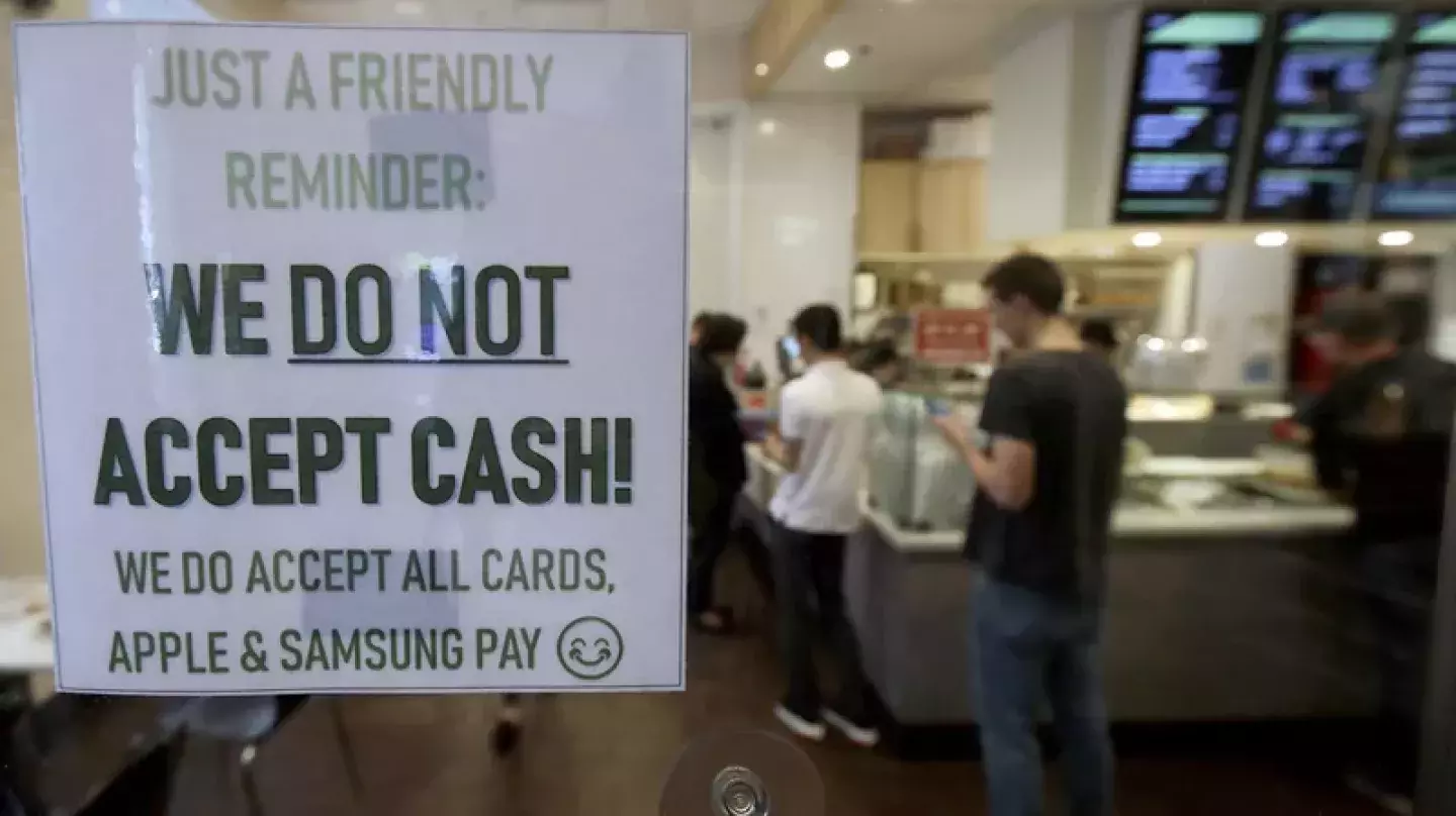 Sign indicating business doesn't accept cash in a restaurant window